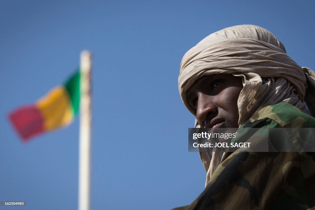 The Malian flag waves in the background while a man stands in focus